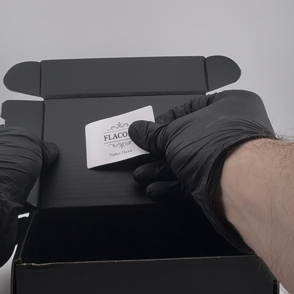 Flacory Sticker wird auf eine schwarze Versandbox geklebt